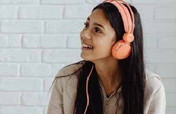 Smiling young adult woman listening to music on headphones